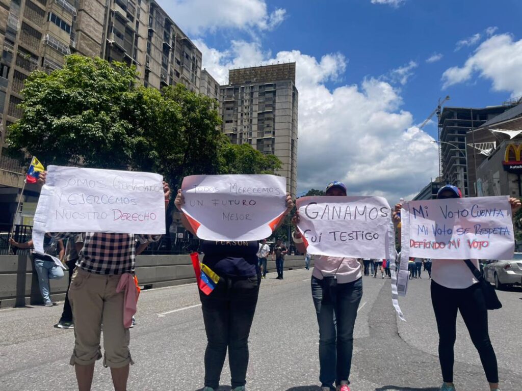 Personas asisten a la manifestación opositora con pancartas y actas electorales impresas