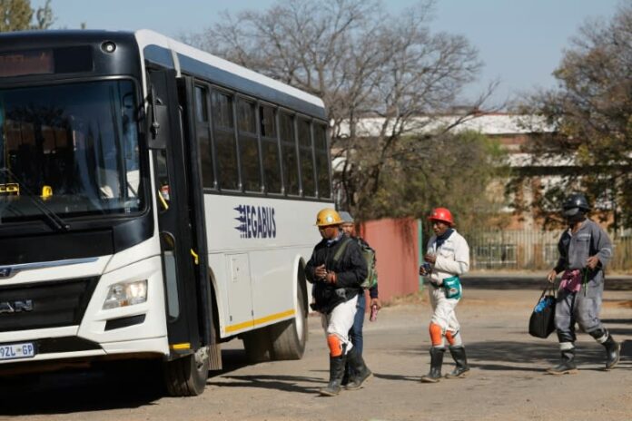 Varios de los 260 mineros que quedaron atrapados en la mina de oro Kloof 7, en Westonaria, Sudáfrica, abordan un autobús