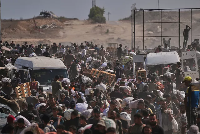 Palestinos llevan paquetes de ayuda humanitaria cerca de un centro de distribución de la Fundación Humanitaria de Gaza en Netzarim