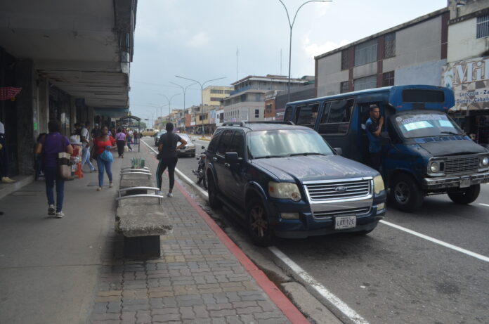 Carros y motos se estacionan en las franjas rojas y amarillas.