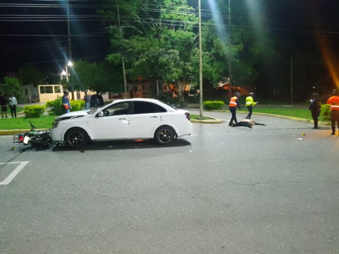 Parte de la moto quedó debajo del parachoque del vehículo Chevrolet Opta, color blanco