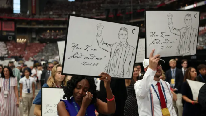 Los asistentes sostienen carteles antes del servicio público en memoria del activista de derecha Charlie Kirk en el estadio State Farm en Glendale, Arizona