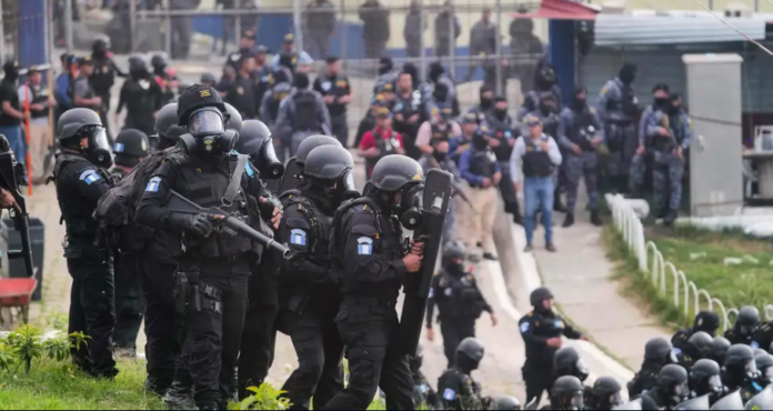 Policías antidisturbios vigilan la entrada al Centro de Detención Preventiva para hombres en Ciudad de Guatemala, tras recuperar el control de esa prisiones donde los miembros de dos pandilla estaban amotinados y con decenas de agentes de rehenes